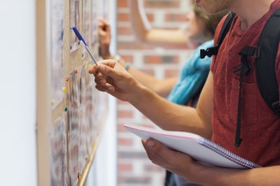 Casual students searching something on notice board in college