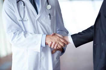 Doctors shaking hands discussing benefits of facility management software in hospitals